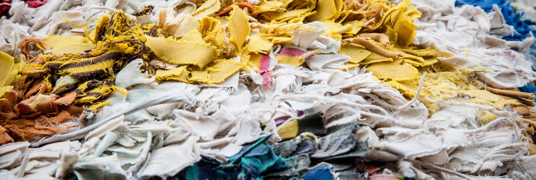 An image of textile scraps in a landfill shows how waste is a real apparel industry issue that requires innovative solutions. 