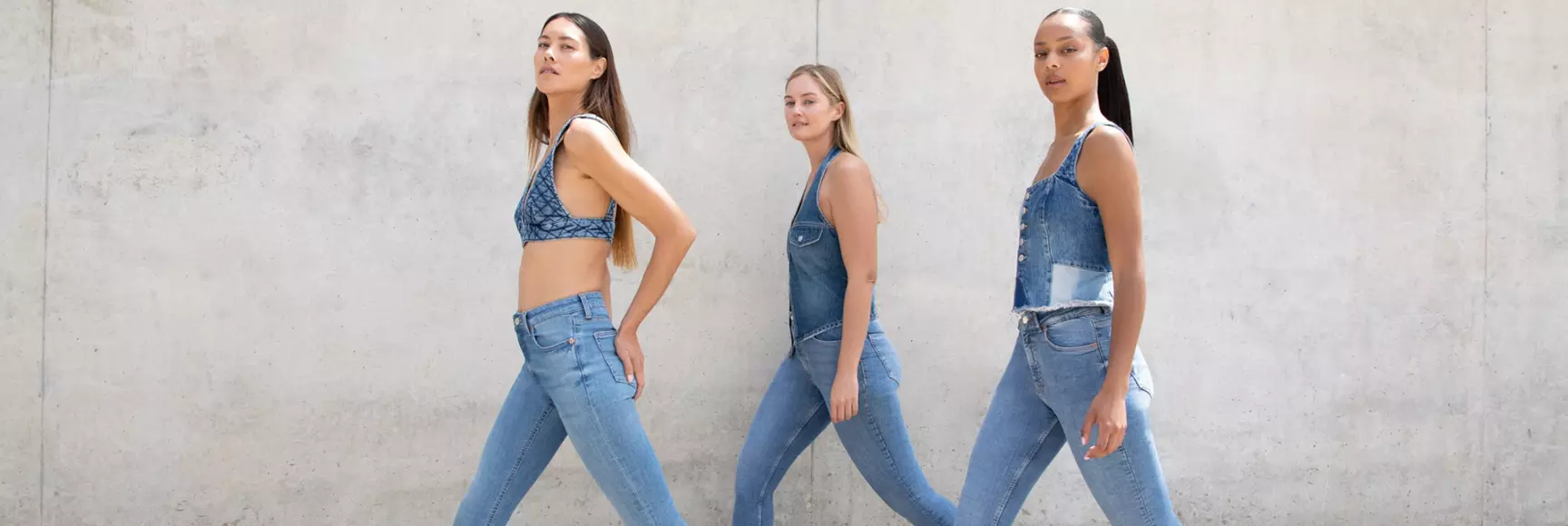 A trio of models walking are showcasing stretch denim jeans with LYCRA® ADAPTIV fiber that adapt to fit different body types.