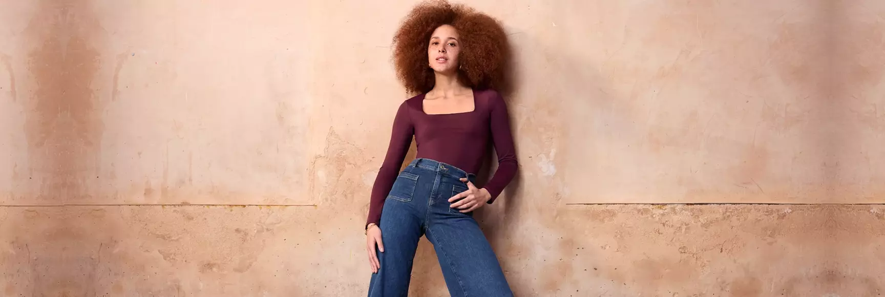 A model wearing purple long sleeve tee and blue jeans 