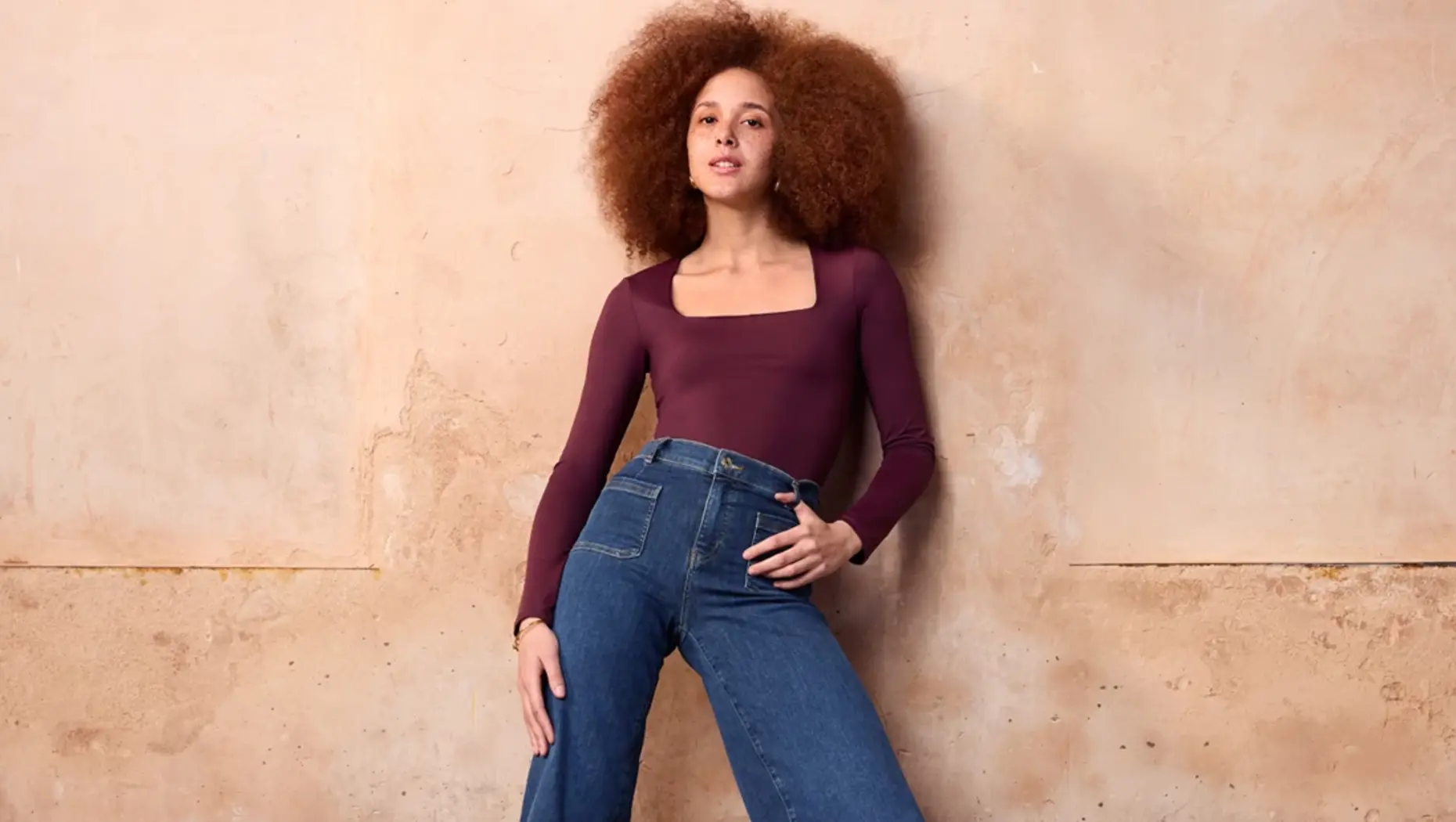 A model wearing purple long sleeve tee and blue jeans 
