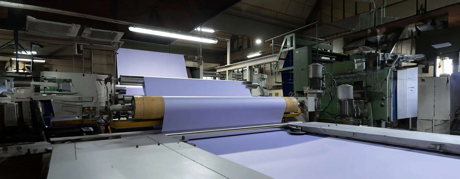 A large roll of purple fabric in a fabric mill.