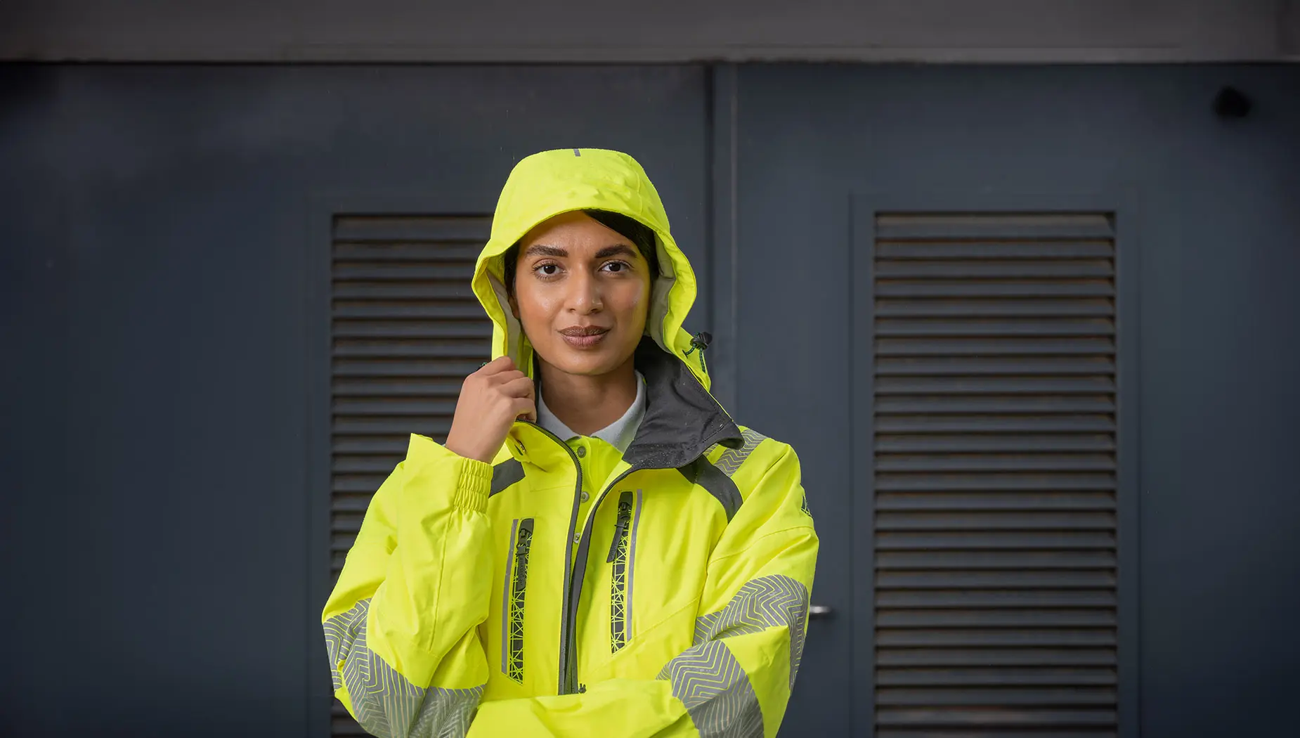 A woman wears a high-vis yellow workwear jacket.