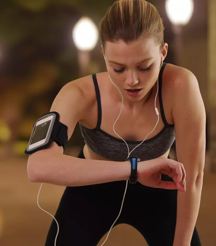 Woman in performance activewear checks her heart rate while jogging to show how technology enhances clothing and life.